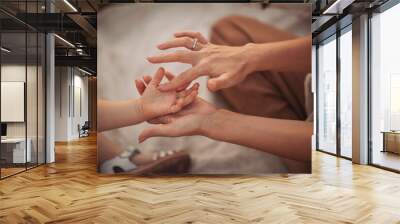 Mother holding hands with her child. Parent play with hands of little kid girl, giving psychological help. Sincere different generations family sharing secrets or making peace. Wall mural