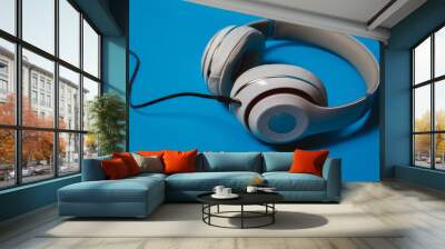 White audio headphones, isolated on blue background. Wall mural