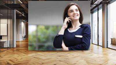 Businesswoman talking at the phone with modern building as backg Wall mural