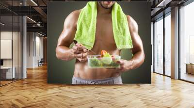 Fitness man holding a bowl of fresh salad on black background Wall mural