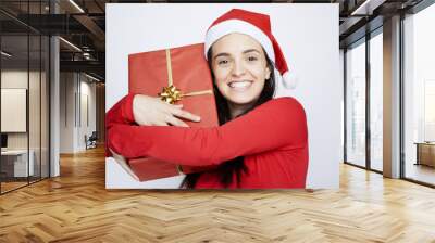 Happy Santa girl holding a gift with satisfaction against gray b Wall mural