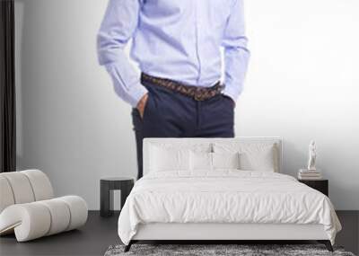 Young business man standing with hands in pockets on a white background Wall mural