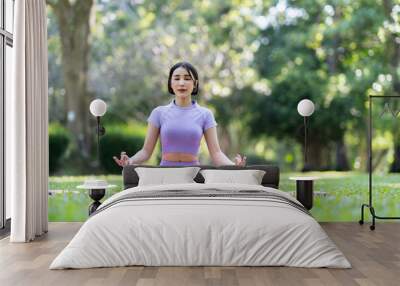 Attractive and strong Asian woman with a beautiful body. meditation relax yoga in an elegant posture in the green park Modern concept of relaxation and health care. Wall mural