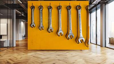 Metal wrenches hanging on a yellow board wall Wall mural