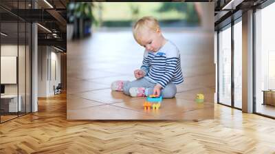 cute little baby girl play with plastic bricks sitting indoors o Wall mural