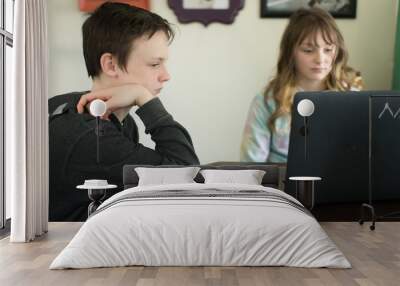 Siblings homeschooling on laptop at kitchen table Wall mural