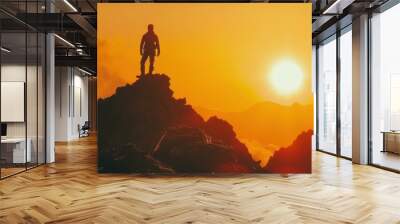 A silhouette of a man standing triumphantly on a mountain peak at sunset, Wall mural