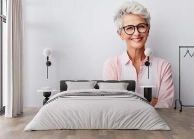 Cheerful pretty older woman in elegant glasses sitting isolated on white background  Wall mural