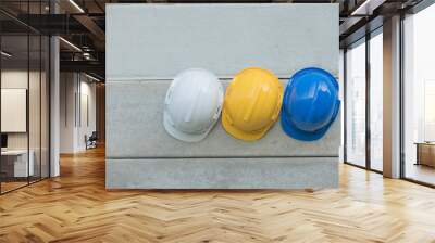 Safety helmet Blue, Yellow, White On the concrete wall,Hats for engineering and construction hang on the cement wall.safety helmet On the concrete Wall mural