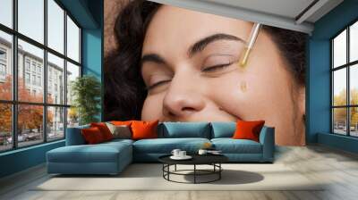 Close-up of young woman applying face serum Wall mural