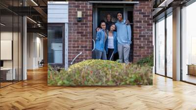 Portrait of family with teenage daughter and son in doorway of new house Wall mural