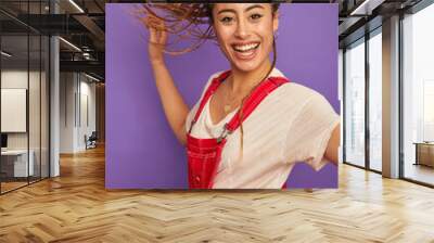 Portrait of smiling woman in white and red clothing against purple background Wall mural