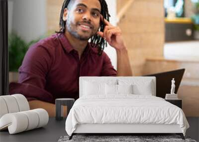 Smiling businessman working on laptop in office Wall mural