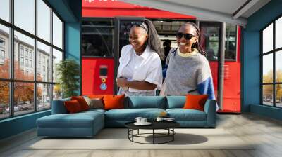 Smiling young women getting off city bus Wall mural