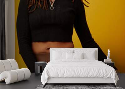 Studio portrait of smiling woman with dreadlocks against yellow background Wall mural