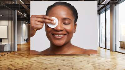 Studio portrait of woman cleaning face with cotton wool Wall mural