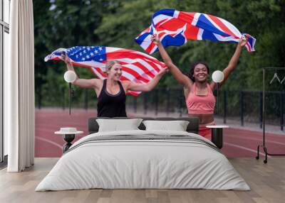 Two female athletes running with flags on running track Wall mural