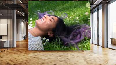 United Kingdom, Smiling woman with black and purple hair and closed eyes lying on grass Wall mural