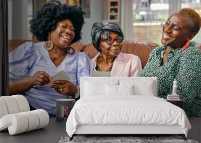 Women and senior mother sitting on sofa and looking at photos Wall mural