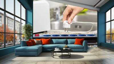 Close up of a woman's hand plugging a toaster into the electrical outlet in a socket on a kitchen counter at home Wall mural