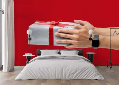 Close up of hand of man holding gift box over red background. Wall mural