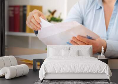 Close up of woman hands putting a letter inside an envelope on a desk at home or office Wall mural