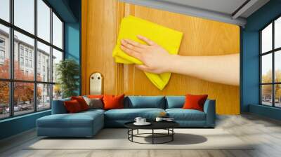 hand cleaning a door with a yellow cloth Wall mural