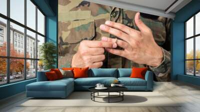 Hands of soldier male who is about to taking off his wedding ring. Wall mural