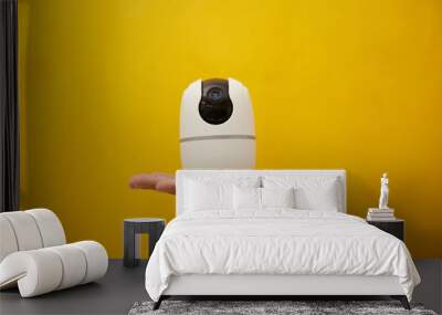 A hand hold a wireless security camera on yellow background  Wall mural