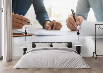 Two people writing and reviewing documents together at a desk. Wall mural