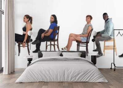 side view of a large group of people dressed in sports and casual clothes sitting on chair over white background Wall mural