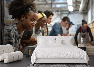 a diverse group of young people in a modern workshop, engaging in hands-on activities such as woodworking, showcasing the development of practical skills and innovation on World Youth Skills Day. Wall mural