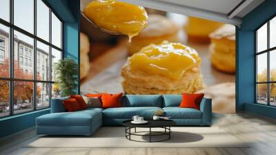 A person is pouring a yellow substance onto a plate of pastries Wall mural