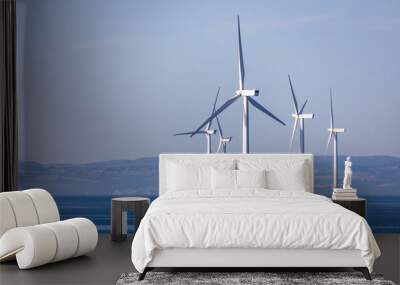 Abstract ethereal view of beautiful giant wind turbines at sea with patchy fog blue sky Wall mural