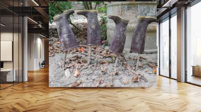 Four dirty rubber boots drying upside down on wood  posts, worker and farmer boots, work break Wall mural