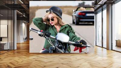 A beautiful young woman sitting on a black and chrome motorbike Wall mural