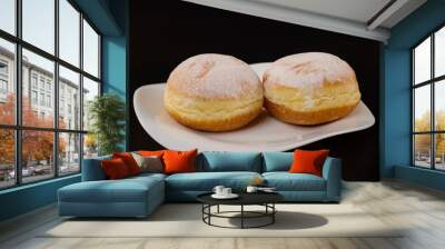 two donuts filled with jam on a white plate on a black background Wall mural