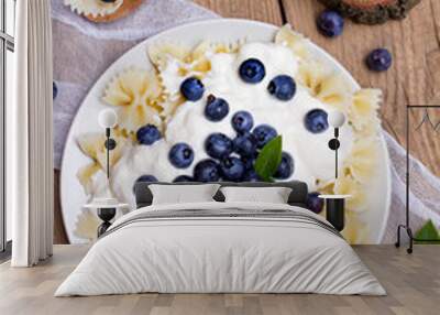 Tasty pasta with fresh organic blueberries and vanilla cream. Sweet dinner on retro wooden table. Wall mural