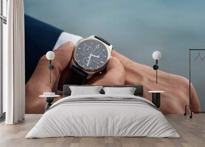 A man in a business suit checking a wrist watch on his hand on background  sea Wall mural