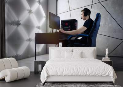 Professional gamer in his expensive studio young man having live stream playing online video game. Cyber sportsman is streaming popular pc computer game for his followers      Wall mural