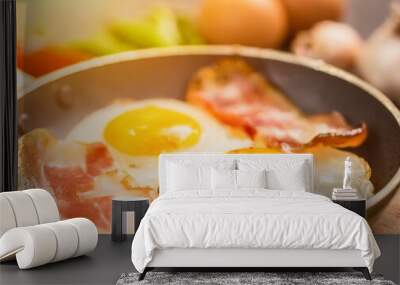 Frying eggs with bacon and fresh pepper for morning meal Wall mural