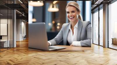 Beautiful blonde business woman working on laptop and smiling sitting at desk in modern office space Wall mural