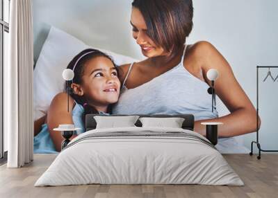 Were bonding. Shot of a cheerful little girl relaxing on the bed with her pregnant mother at home during the day. Wall mural