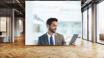 Engaging with the global market. a young businessman using a digital tablet in an office. Wall mural