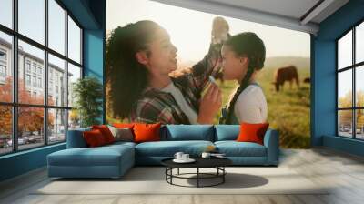 Cows, farm and mother bonding with child, fixing hair clip and standing on field. Farming, farm animals and mom with daughter in the morning enjoying sunrise in countryside showing love and affection Wall mural