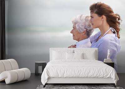 Looking back on their love-filled years together. Shot of a beautiful young woman and her senior mother on the beach. Wall mural