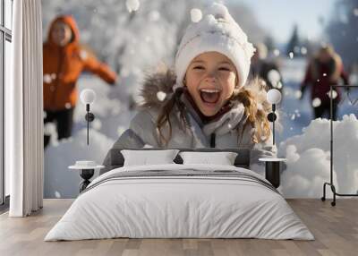 Adorable little girl having fun in beautiful winter park during snowfall Wall mural