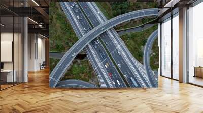 Top down aerial view from drone on modern traffic junction of multiple lane highway road in metropolis city. Heavy traffic on motorways. Elevated curved roads, clover shape bridge with no speed limit. Wall mural