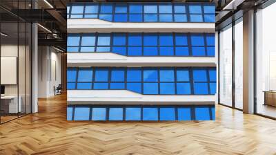 The blue sky is reflected in the windows of a multi-story office building. Abstract city background. Wall mural