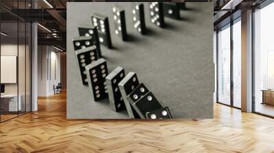 Black dominoes chain on dark table background Wall mural